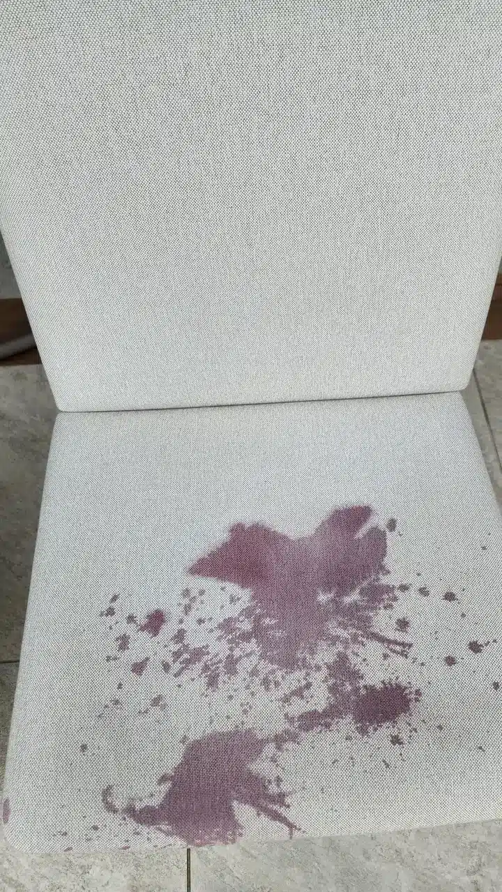 Antes: cadeira de tecido claro com mancha roxa